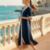 Vestido midi de estilo camisero en color azul marino con detalles en contraste blanco. Presenta cierre frontal de botones, manga corta con vuelta y aberturas laterales en el bajo que aportan movimiento, ideal para un look náutico sofisticado y fresco.