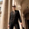 Cazadora tipo bomber confeccionada en un delicado encaje floral negro con sutiles transparencias. Presenta cierre frontal de cremallera dorada, bolsillos de plastrón con solapa y acabados elásticos en puños y cintura, combinando un patrón deportivo con un tejido de máxima sofisticación